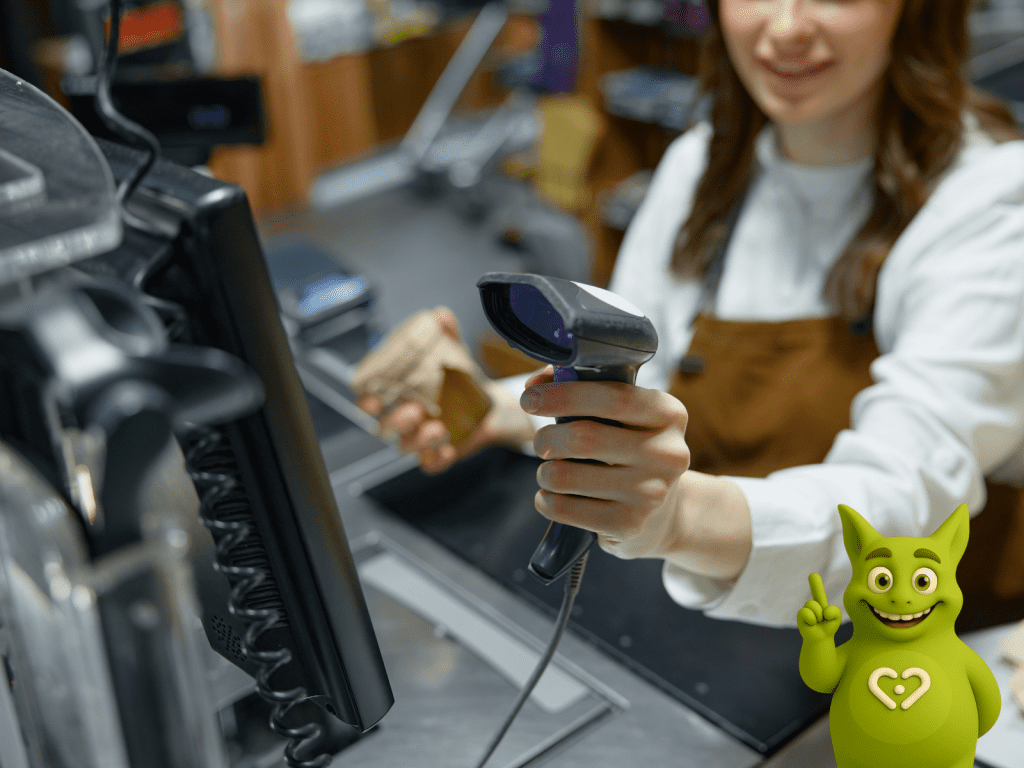 Cashier scanning product at checkout, Tuutuu mascot pointing up next to POS system.
