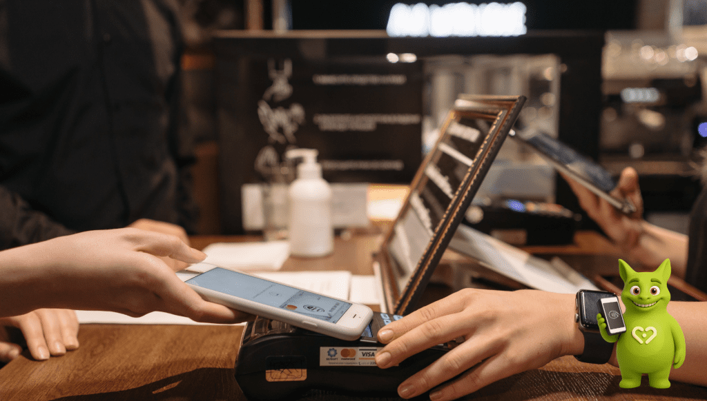 Customer paying with phone via terminal, Tuutuu mascot holding smartphone with fingerprint icon.